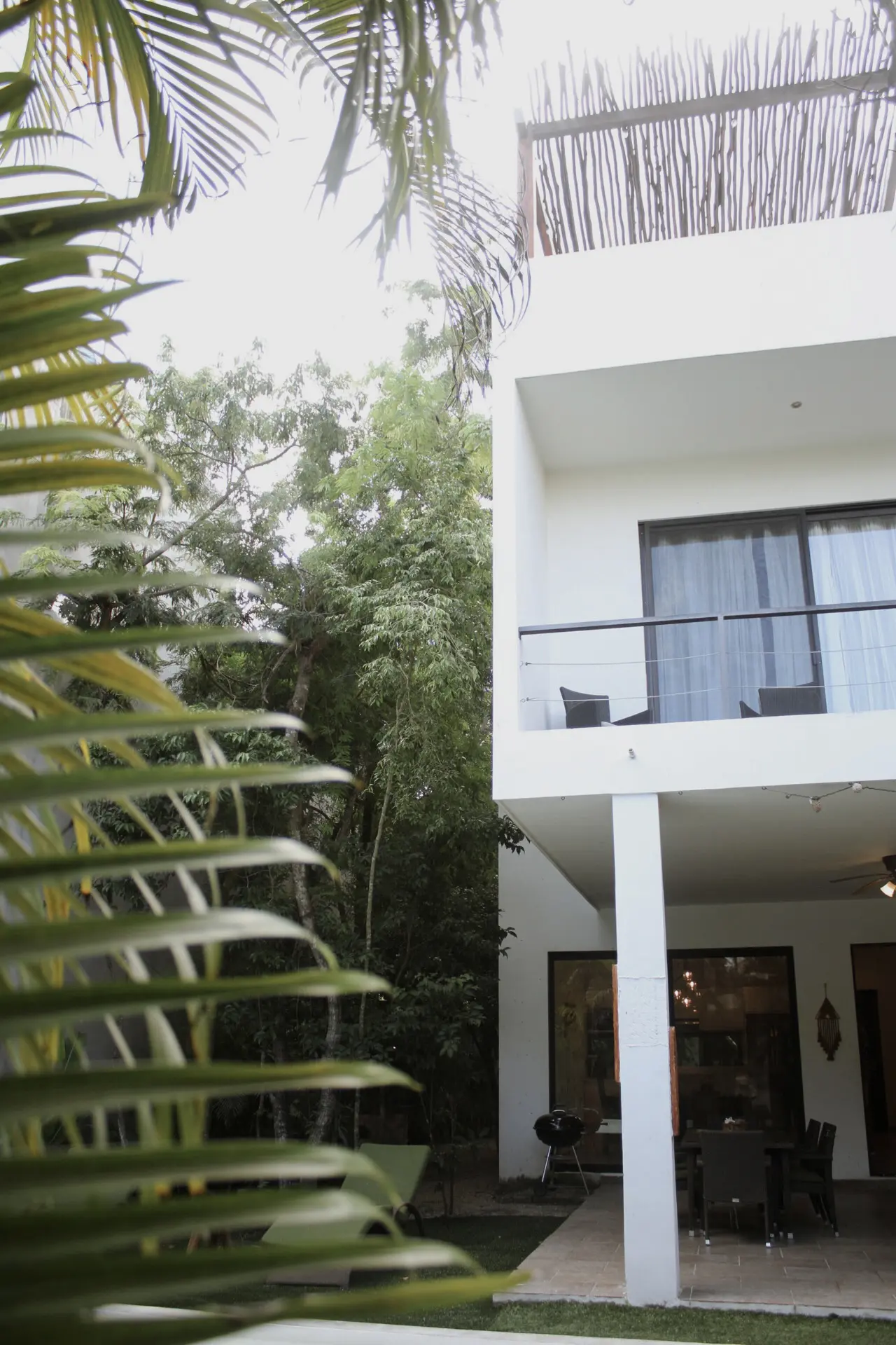 White two-story house with balcony and palms