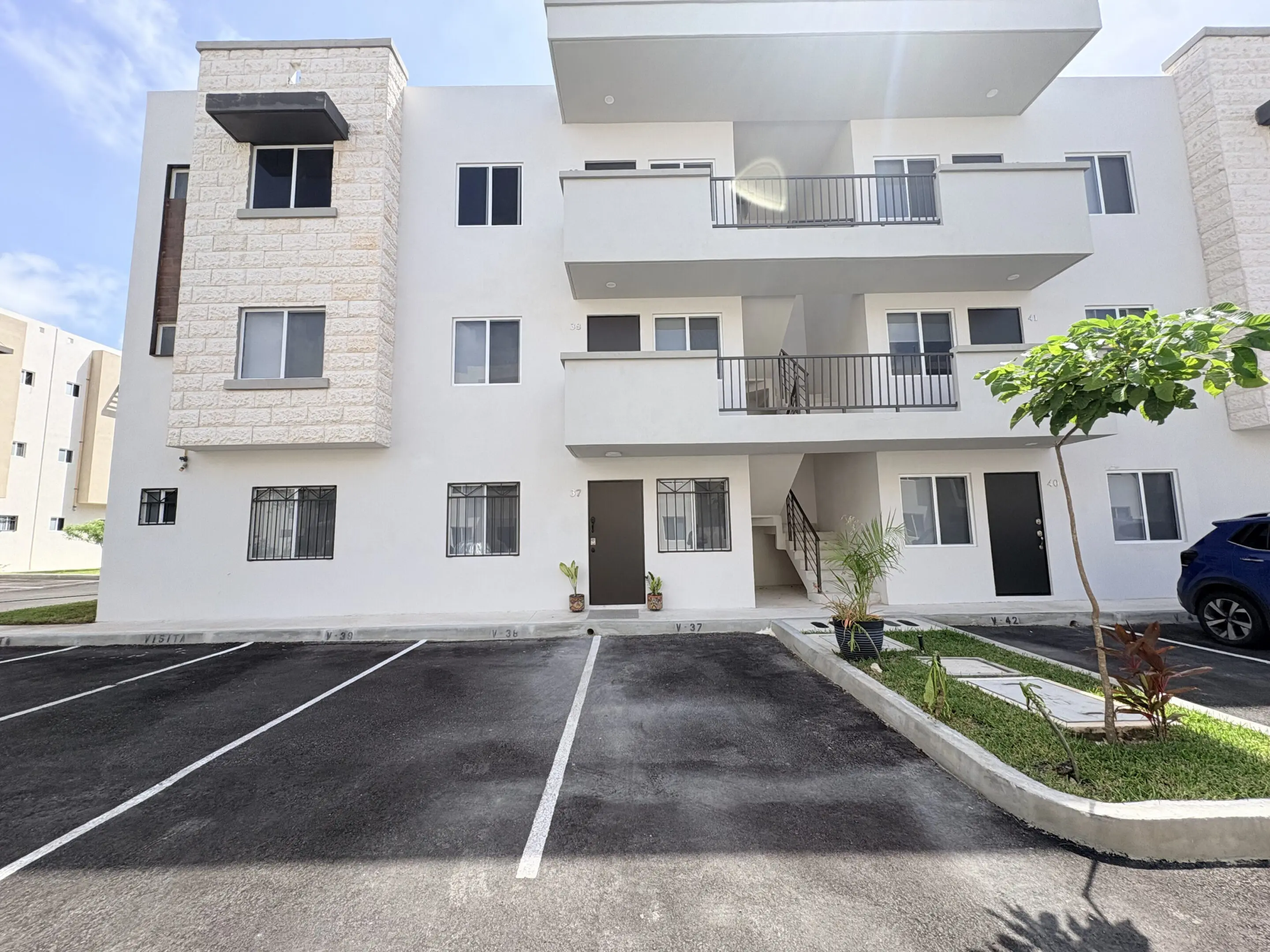 White apartment building with balconies and parking