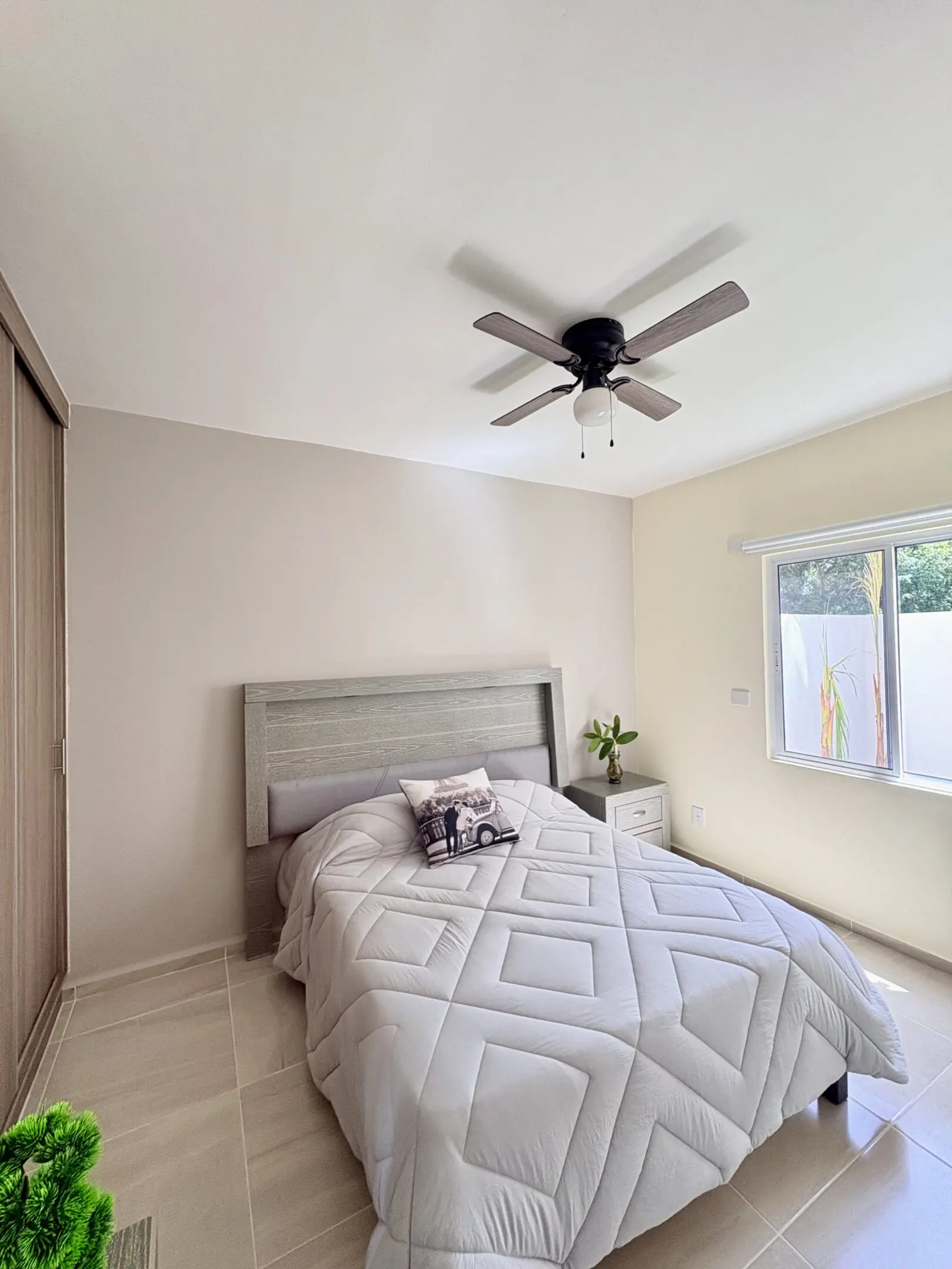Minimalist bedroom with gray bed and fan