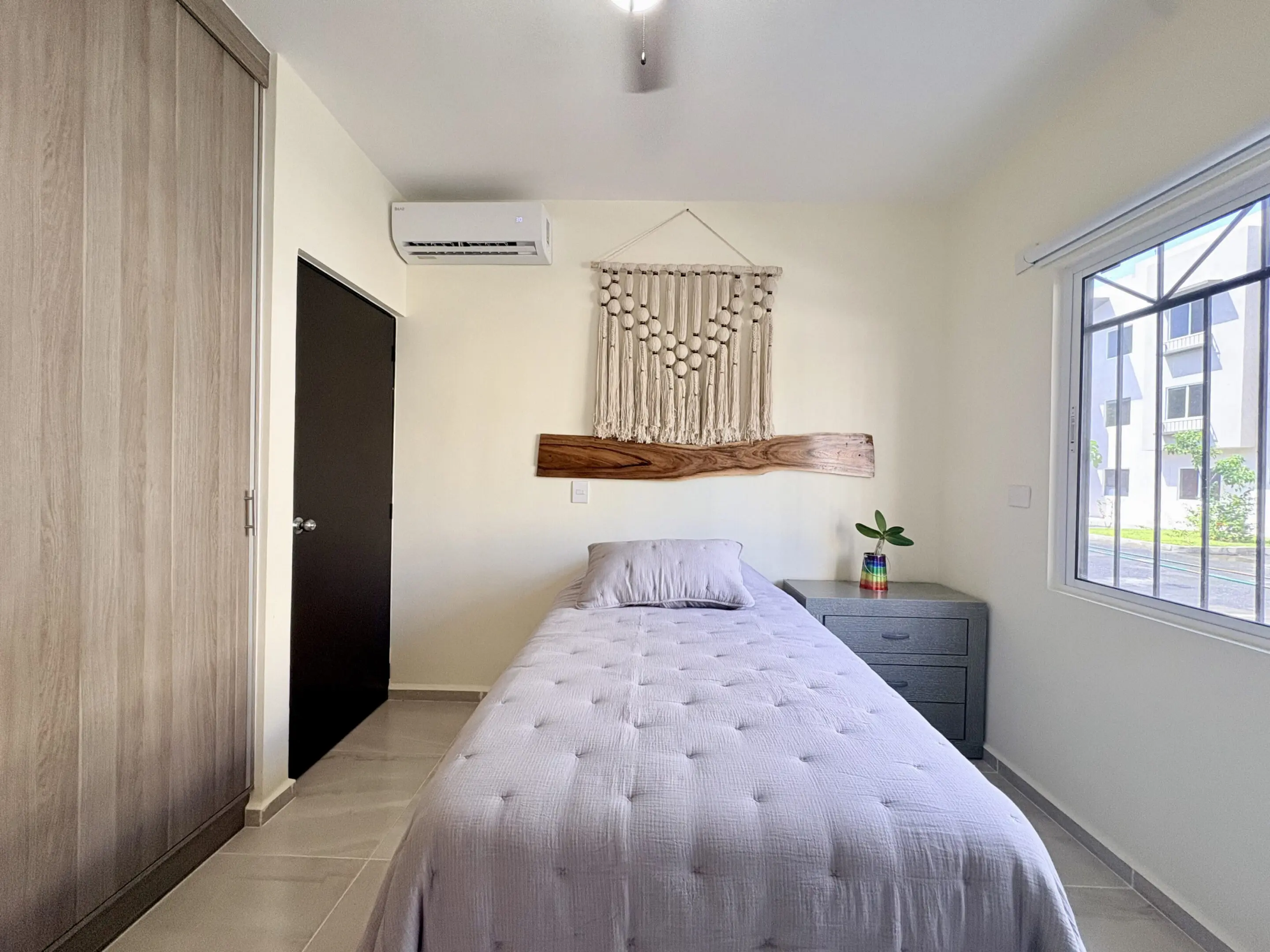 Minimal single bedroom with macrame wall hanging