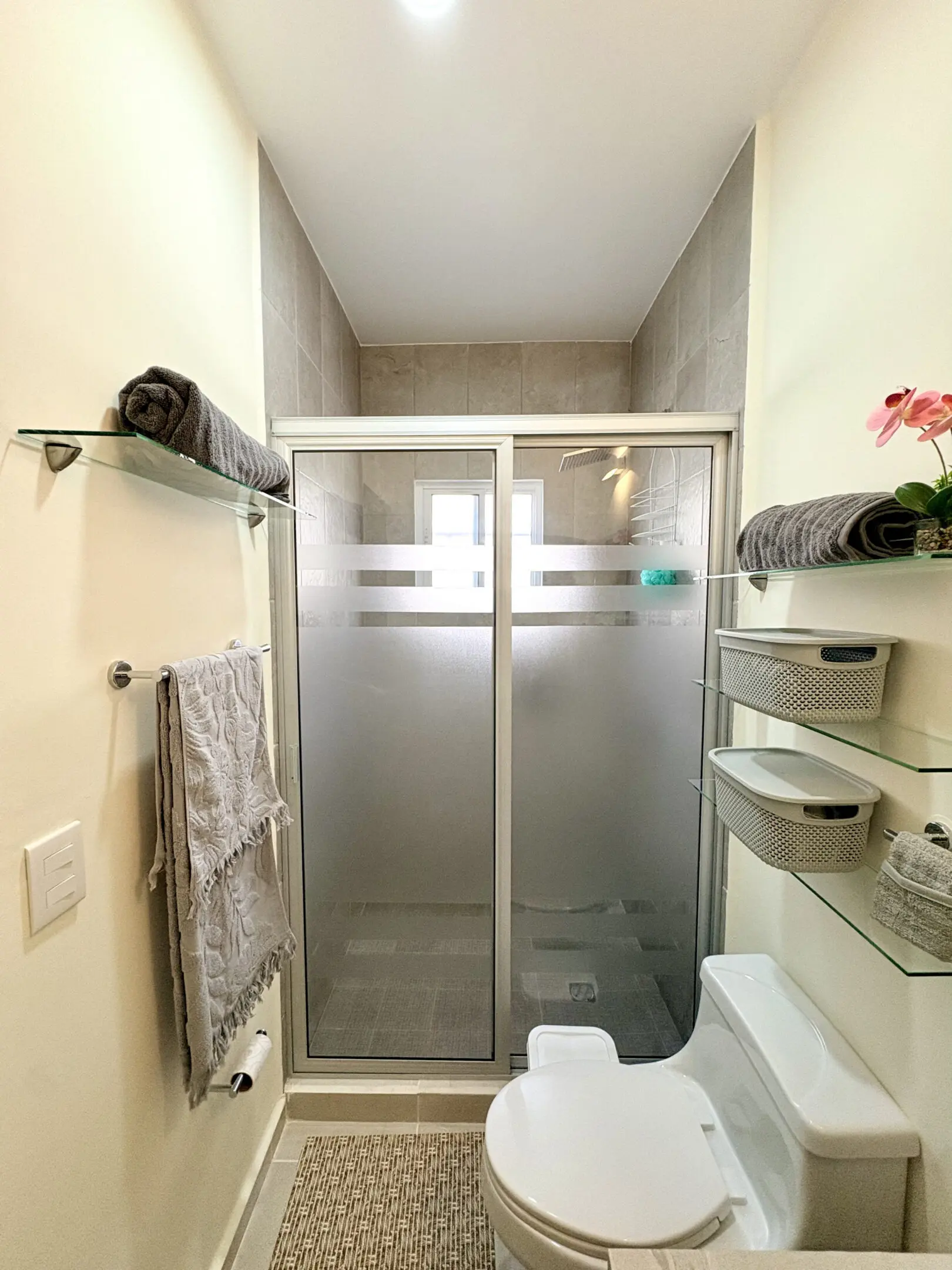 Small modern bathroom with glass shower and toilet