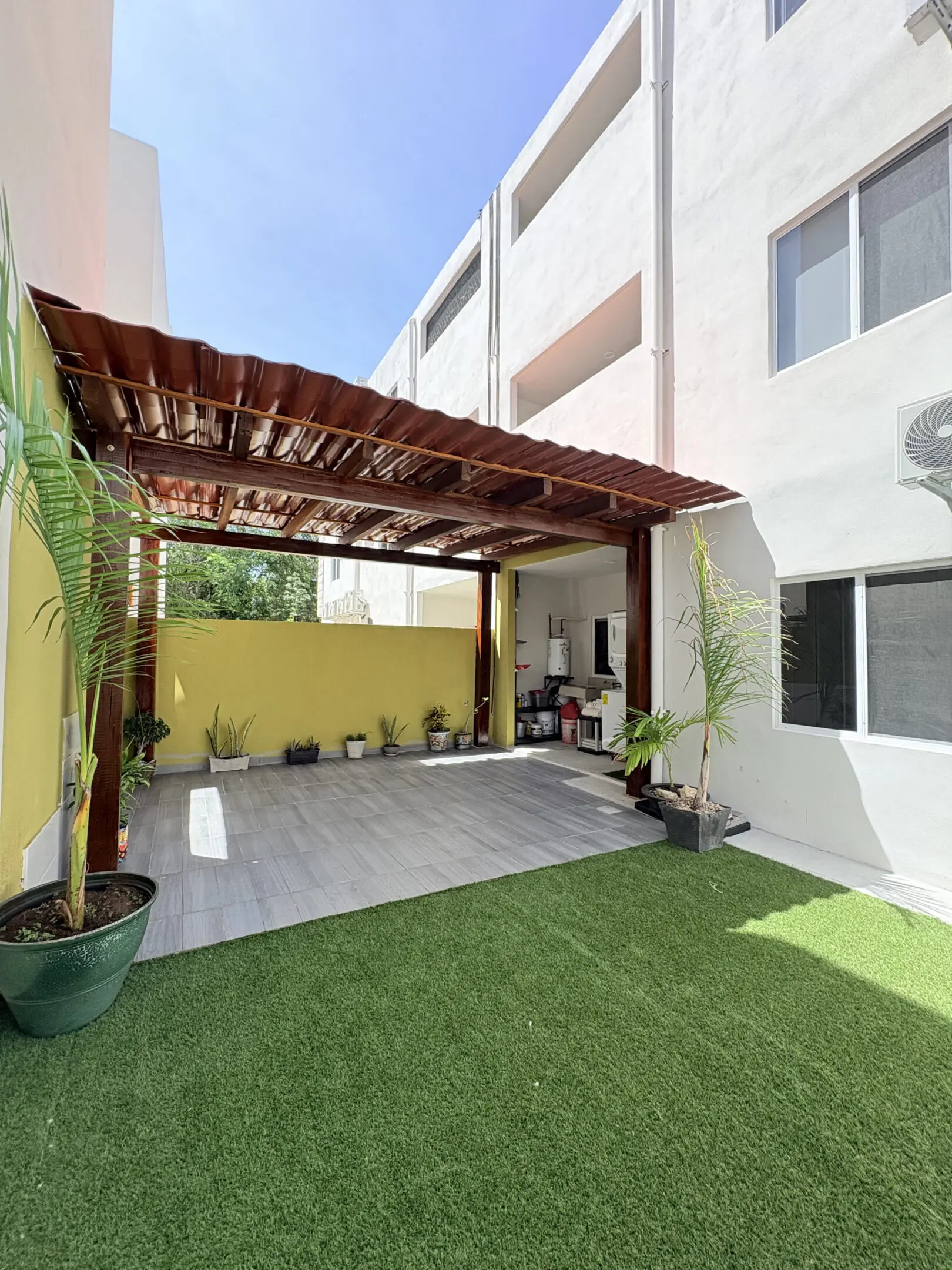 Courtyard with pergola, artificial turf, potted plants