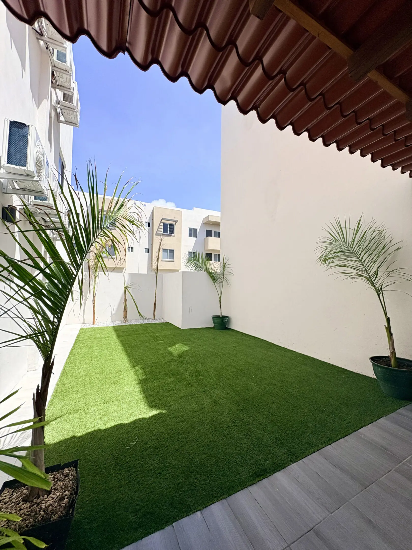 Sunlit courtyard with artificial turf and palms