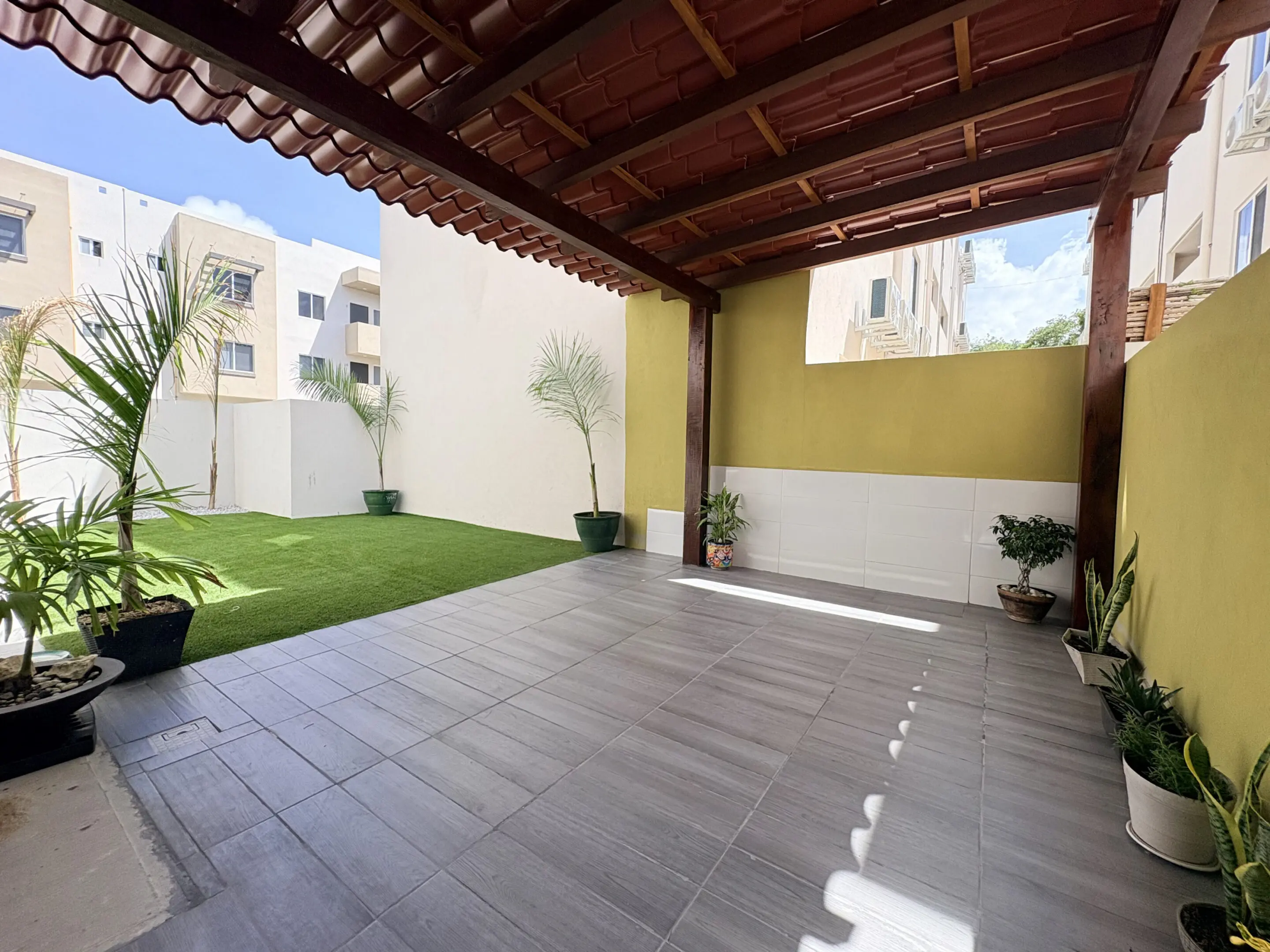 Covered patio with potted plants and lawn