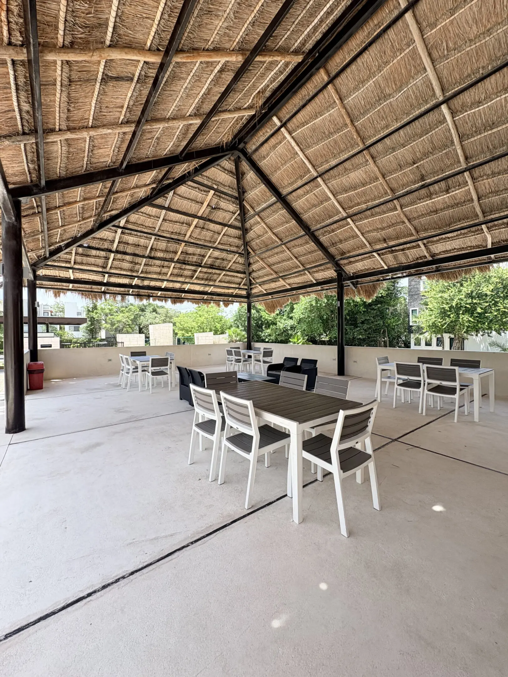 Thatched-roof outdoor pavilion with tables and chairs