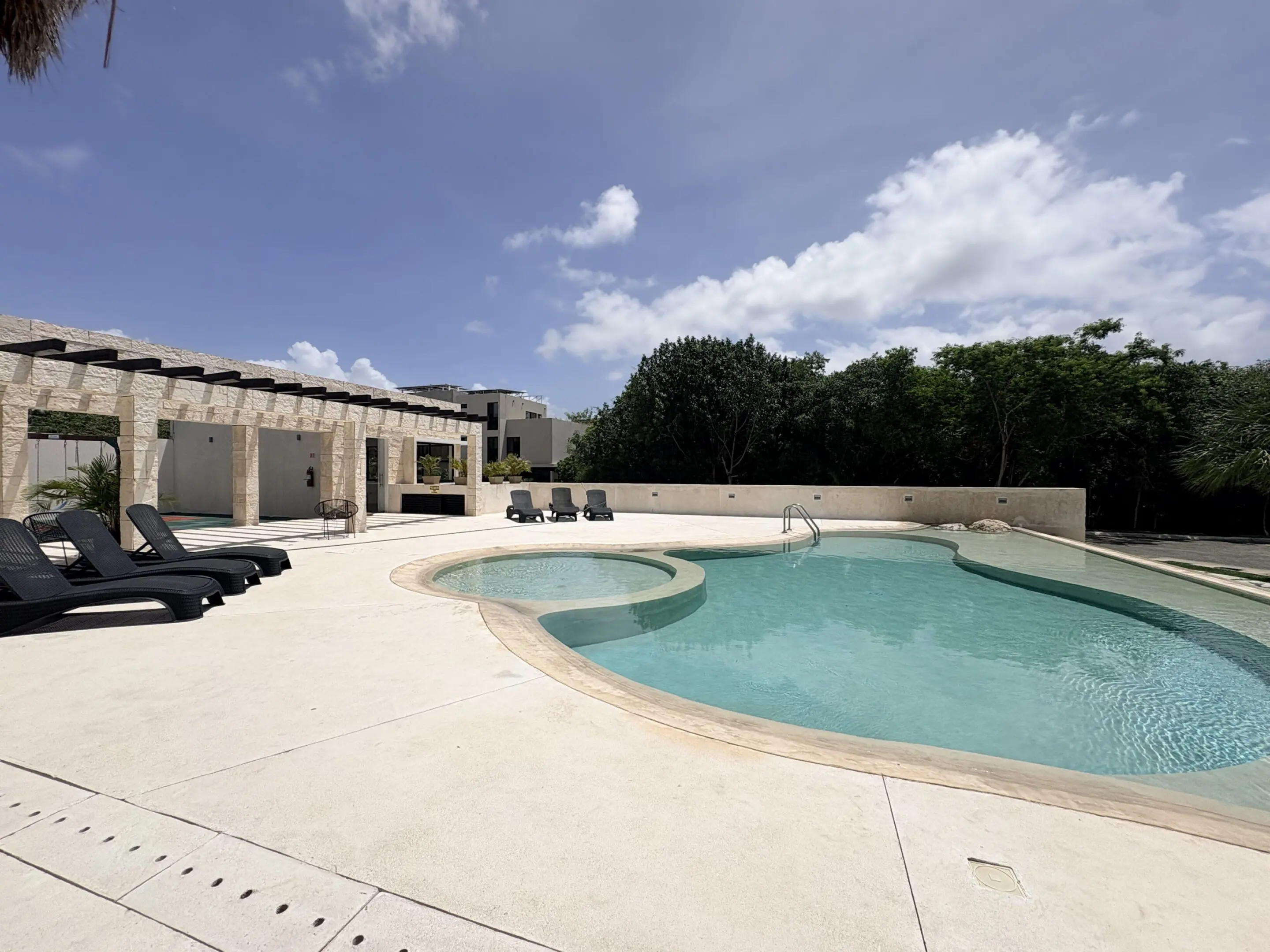 Outdoor curved swimming pool with lounge chairs