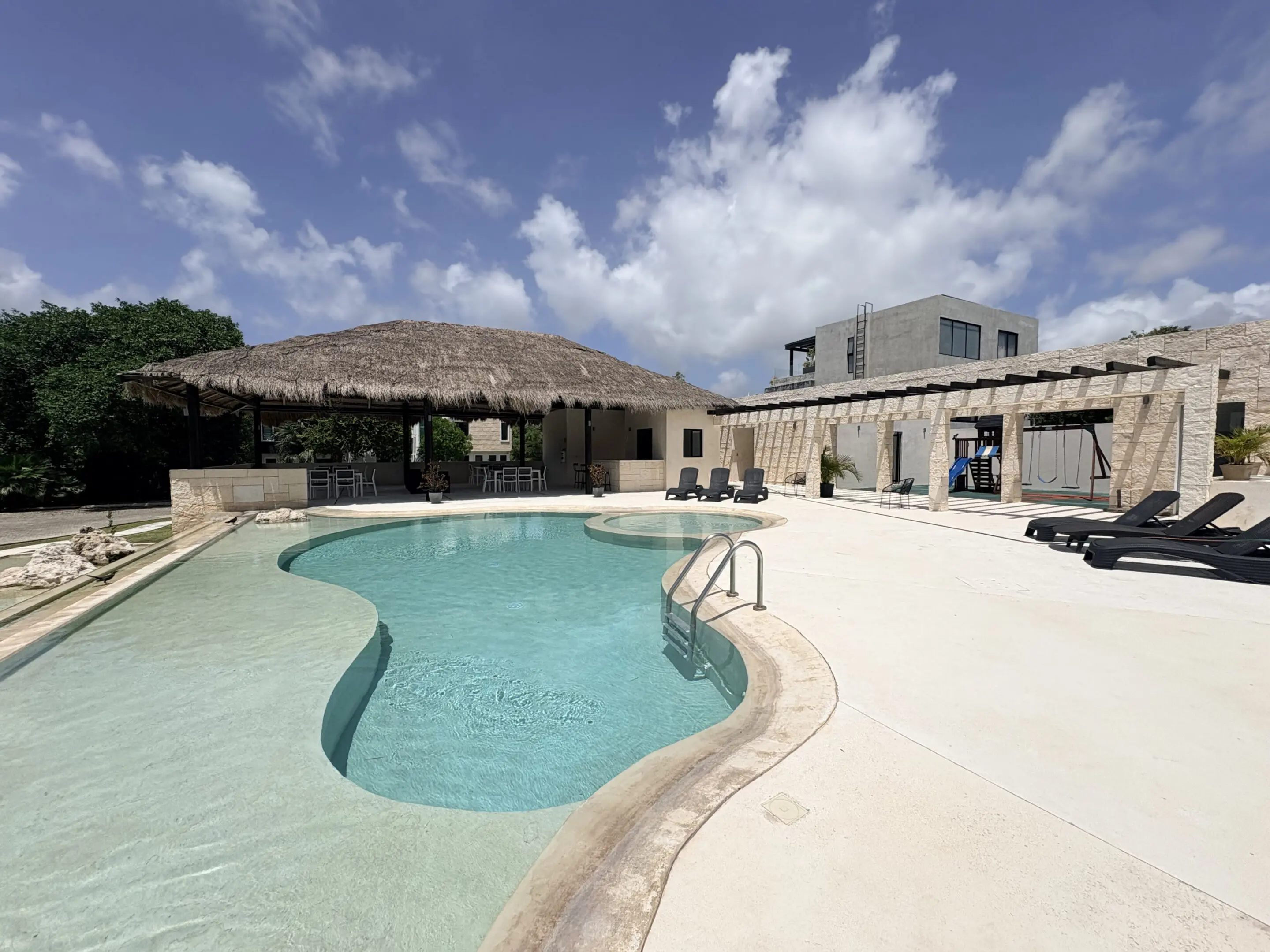 Curved outdoor pool with thatched palapa