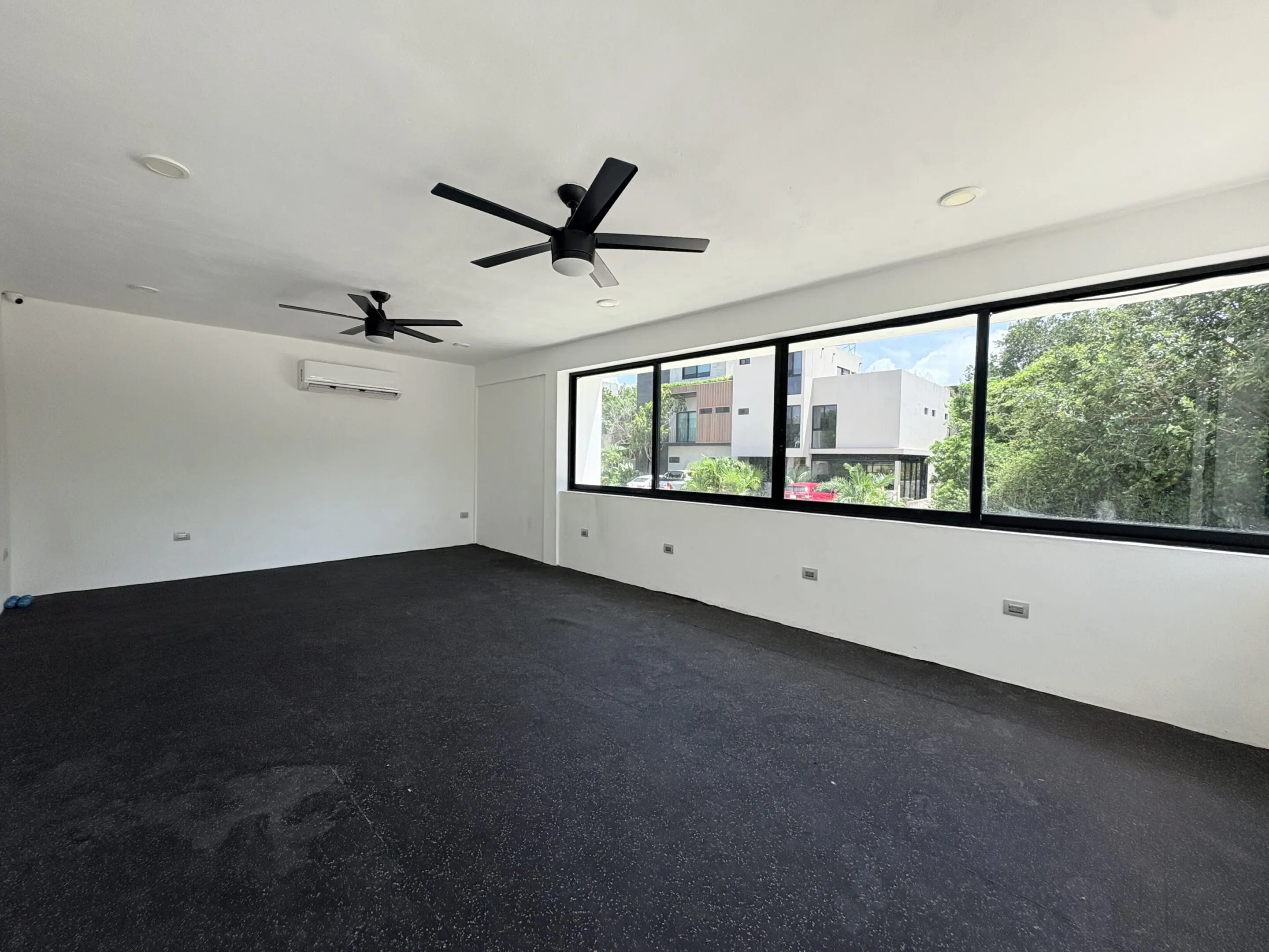 Empty modern room with ceiling fans and windows