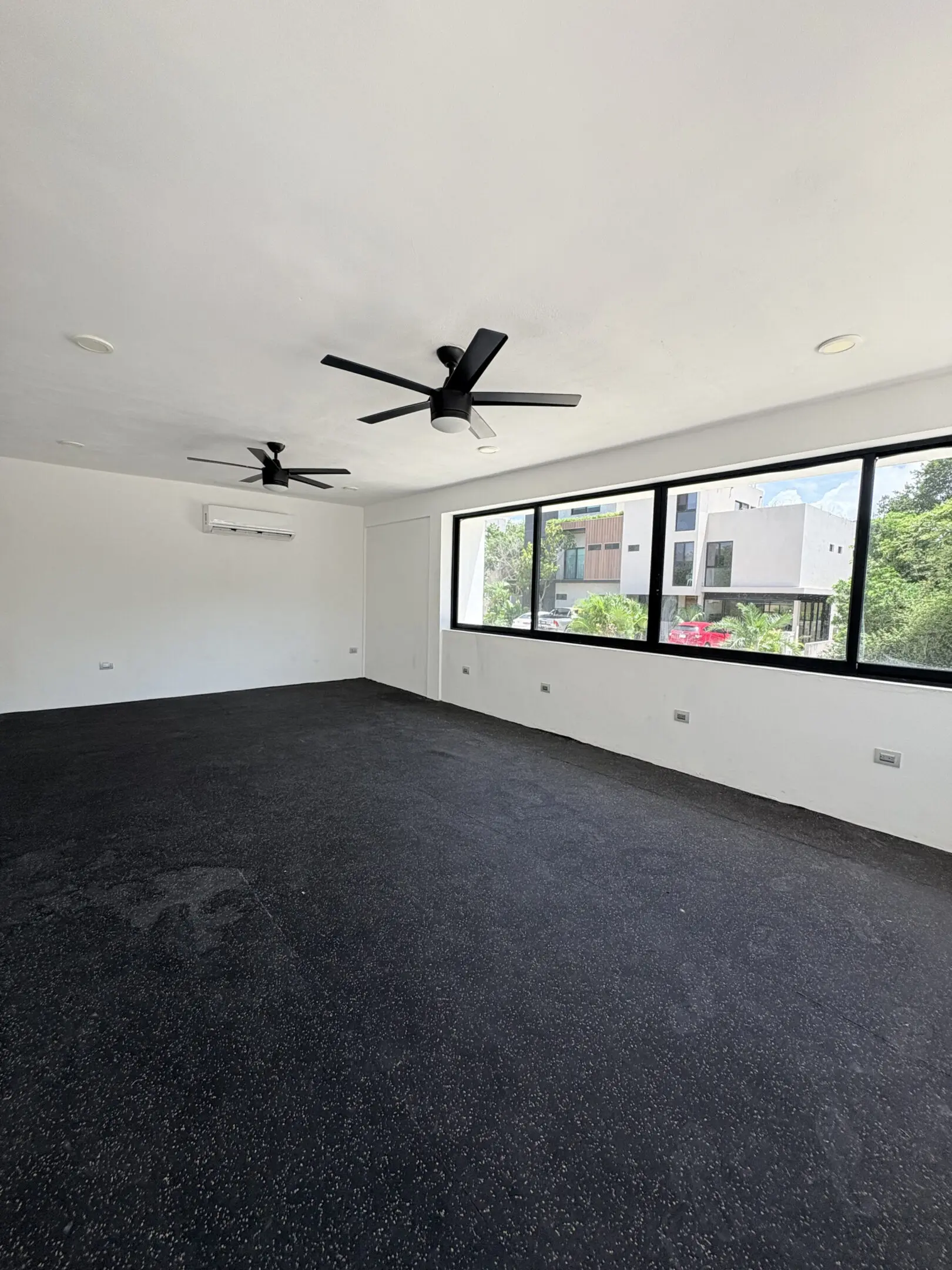 Empty modern room with black carpet and fans