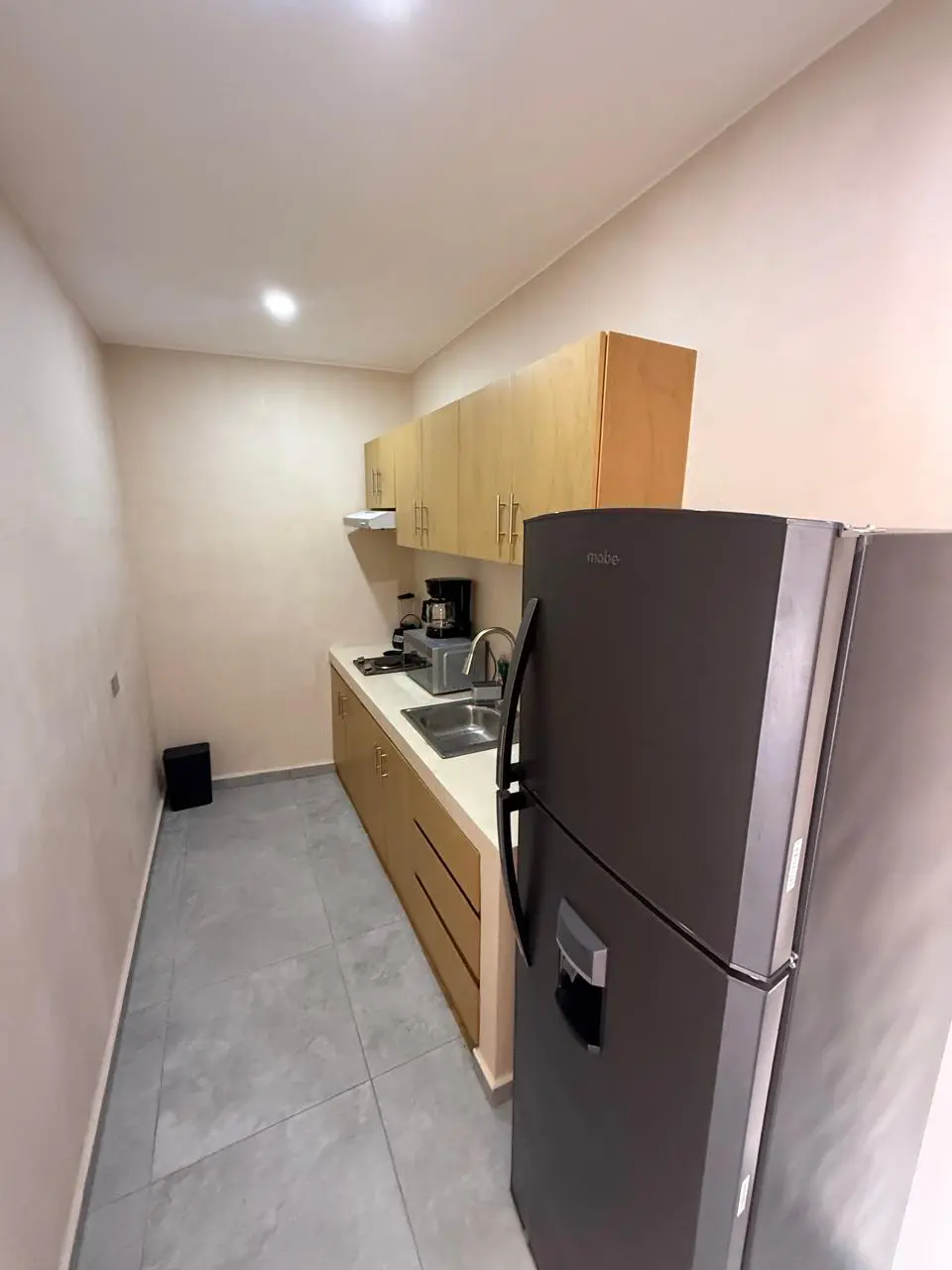 Small galley kitchen with wooden cabinets, fridge