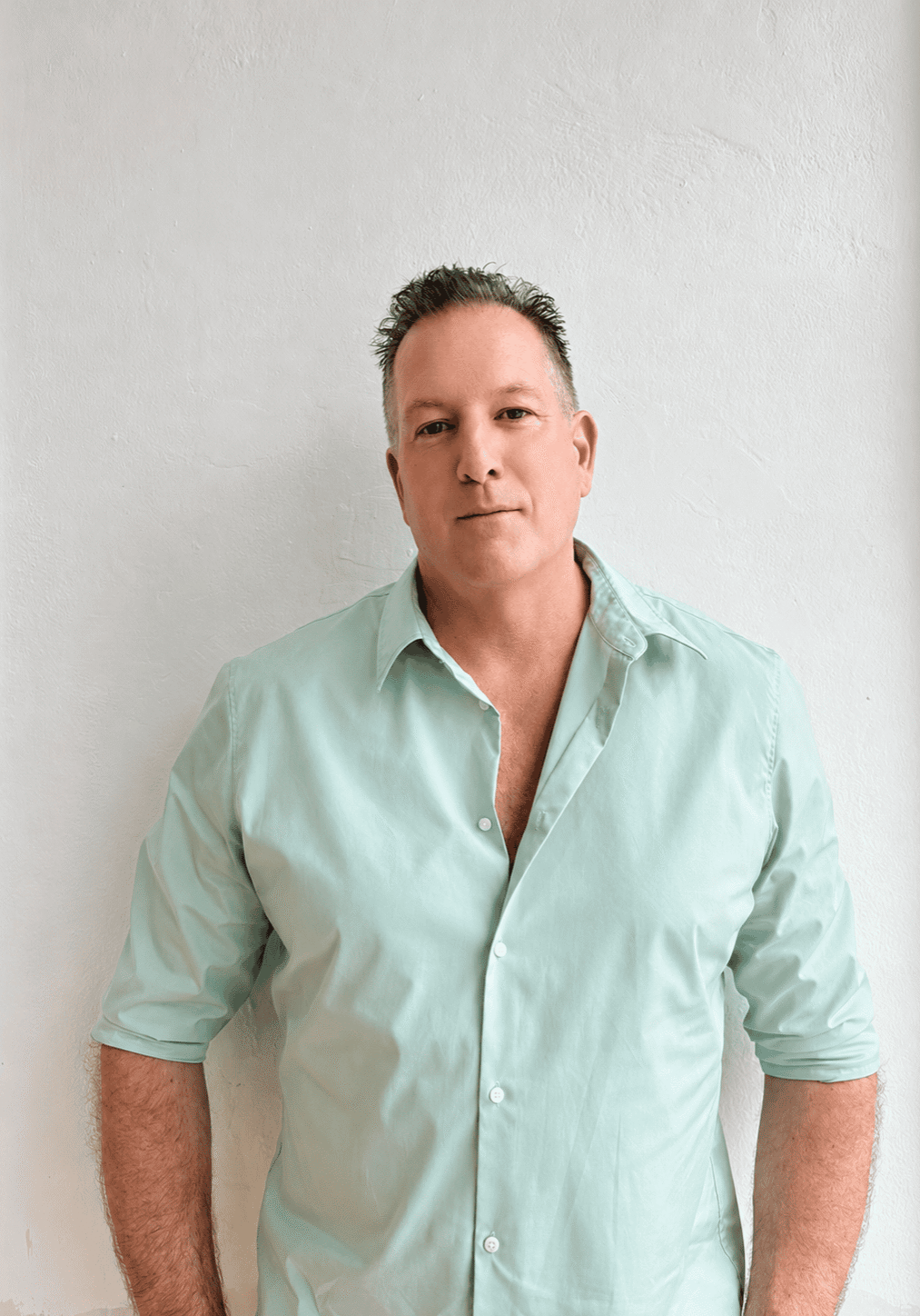 Man in mint shirt standing against wall